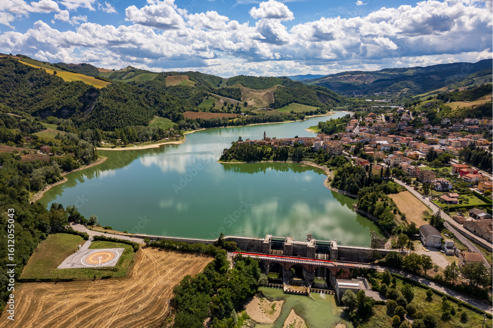 Naklejka premium Panoramic aerial drone view of the medieval village of Sassocorvaro above the Mercatale dam, in the province of Pesaro Urbino, Marche, Italy. The village exudes peace, serenity, and ancient history.
