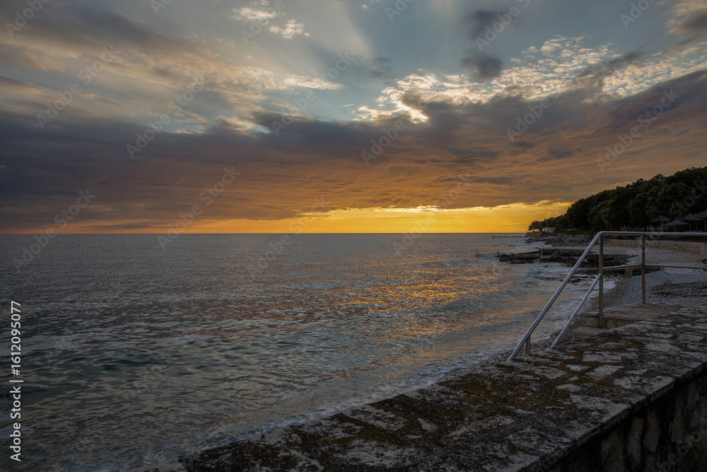 Obraz premium Golden sunset over calm ocean with pier and beach