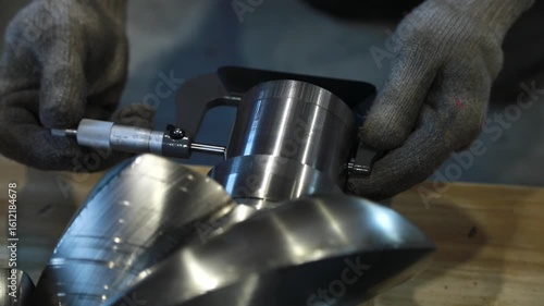 Technician measuring metal part with micrometer