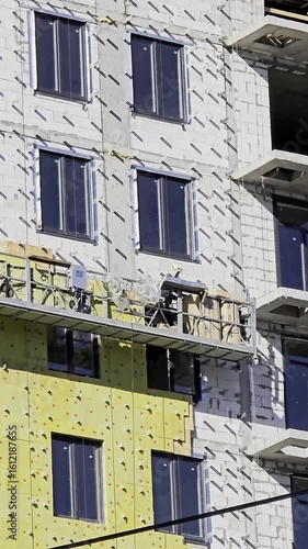 Construction workers installing thermal insulation on building facade