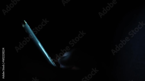 Fingers glow faintly as they tap a smartphone screen in near-total darkness capturing a secretive late-night texting moment filled with isolation tension and digital obsession