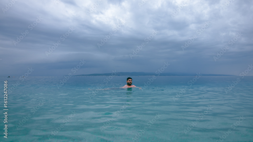 Fototapeta premium Man swimming in turquoise Adriatic Sea in Croatia