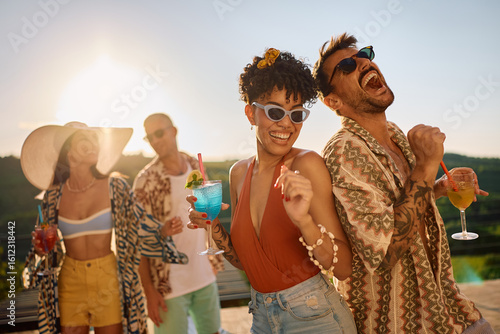 Photography Young cheerful friends dancing while drinking cocktails at summer party
