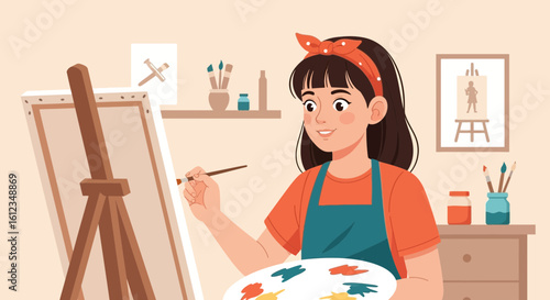 Cheerful artist girl painting on canvas in her studio surrounded by art supplies