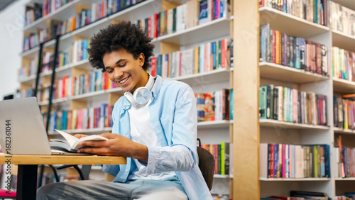 Cuadro en lienzo Cheerful African American male student studying in library, learning online prep