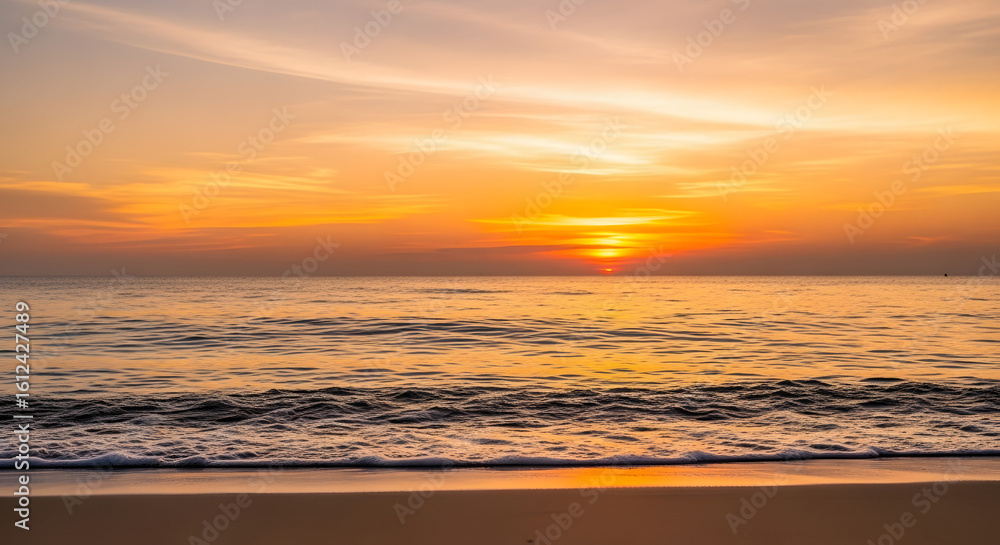 Obraz premium The sun sets over the tranquil ocean, casting a golden glow on the beach