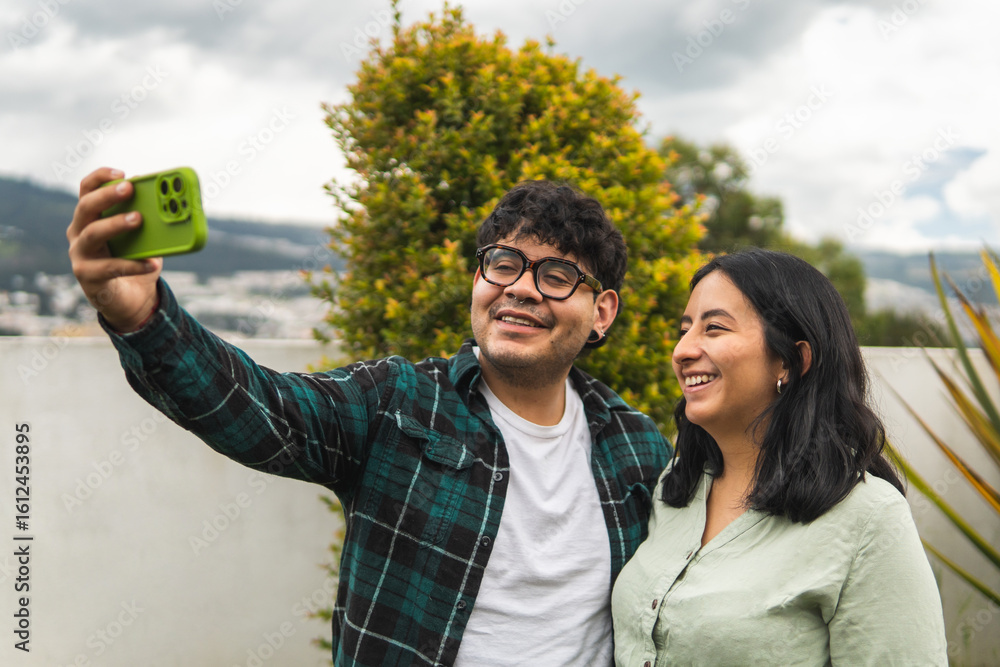 Fototapeta premium Latin american couple taking a selfie outdoors with smartphone