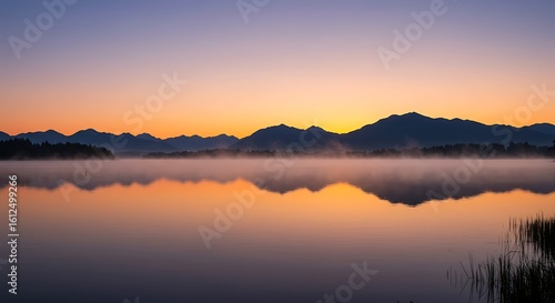 Wallpaper Mural Peaceful Lake Sunrise with Mist over Water Reflecting Golden Sky and Mountain Silhouette in Background Serene Morning Landscape Torontodigital.ca