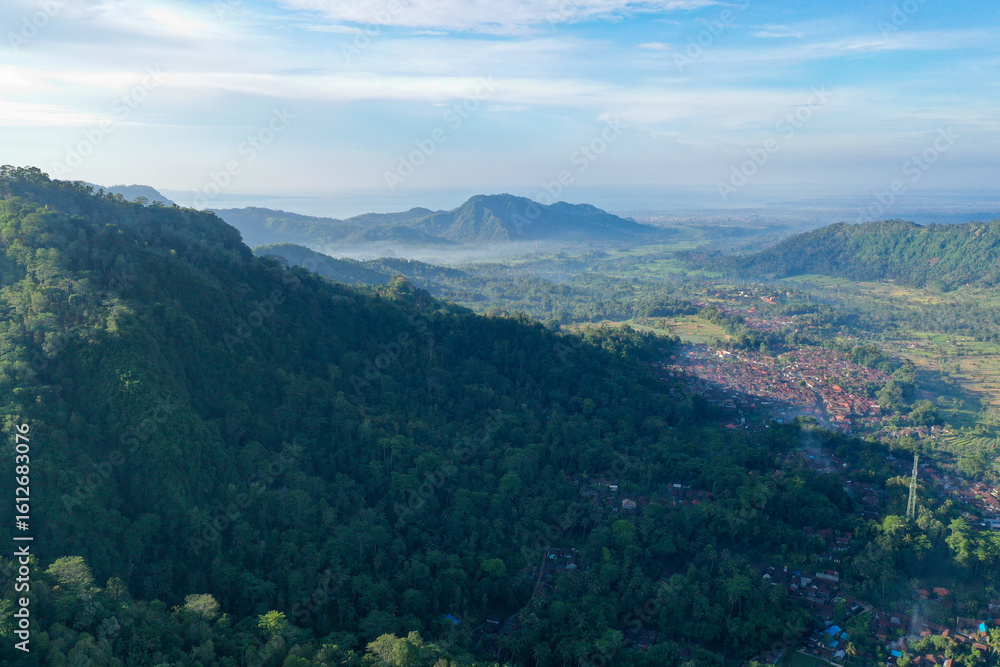 Naklejka premium Forest-Covered Mountain Slopes Casting Shadows Over the Valley