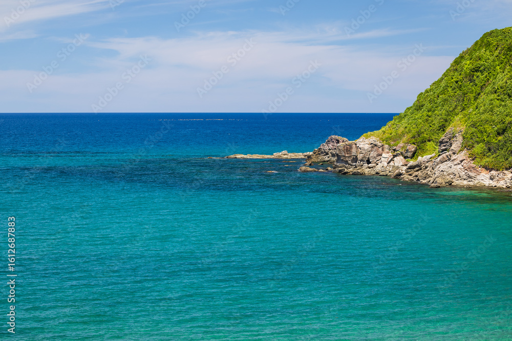 Fototapeta premium 澄んだエメラルドブルーの海と岩場の風景