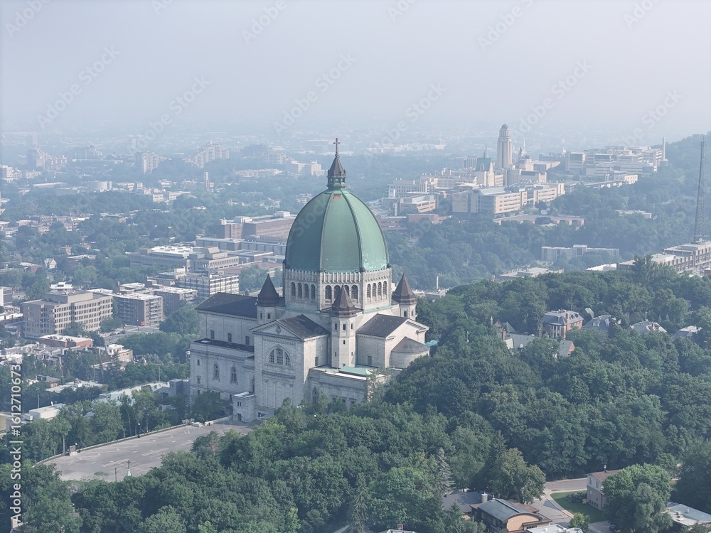 Fototapeta premium Aerial view of Saint Joseph's Oratory in Montreal under heavy smog, haze and forested hills. c.