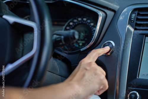 Close-up of hand pressing start button to turn on car engine. Keyless ignition system in modern car