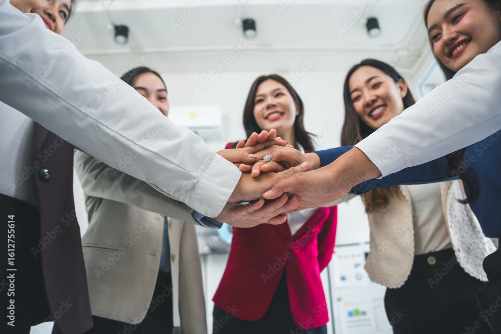 Obraz premium Group of happy diverse businesspeople joining hands together, celebrating project success, demonstrating corporate unity and teamwork in modern office