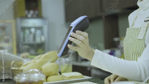 Customer Scanning Fresh Bread and Drinks at Cafe Counter with Smartphone Technology, Showcasing Lively and Inviting Food Atmosphere
