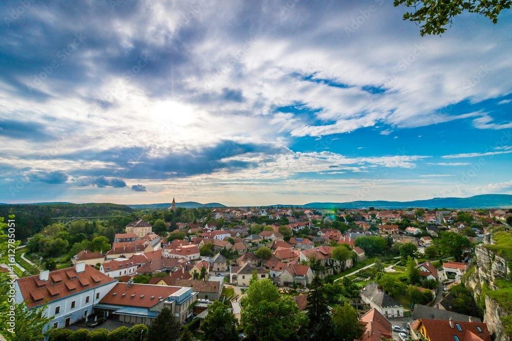 Fototapeta premium Scenic Small Town with Red Roofs Surrounded by Hills and Greenery