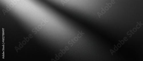 Close-up of a textured black surface with a subtle diagonal light gradient shining across it.