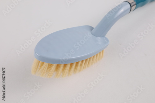 Hard bristle cleaning brush with long blue handle and ergonomic gray grip, isolated on white background