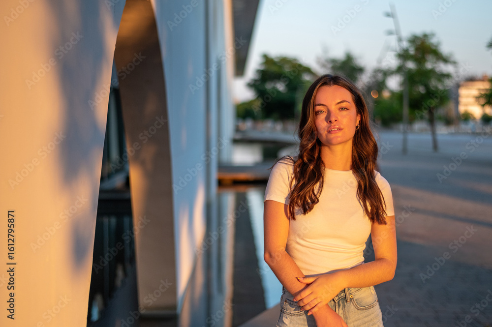 Young woman posing in golden hour light near modern building Young woman posing in golden hour light near modern building