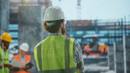 Tablou pe pânză Construction supervisor overseeing building operations at site with team discuss