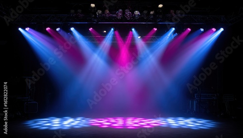 Illuminated Stage. A dark stage is lit by bright beams of blue and pink spotlights shining down from above. The floor glows in a grid-like pattern of blended colors, with a metal structure above