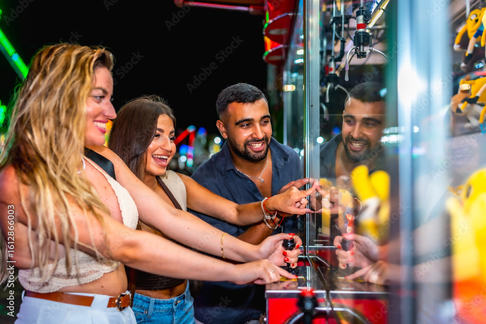 Obraz premium Friends playing crane game at amusement park at night