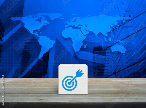 Fototapeta Naklejka Na Ścianę i Meble -  Target with dart flat icon on white block cube on wooden table over world map, modern office city tower and skyscraper, Business success concept, Elements of this image furnished by NASA