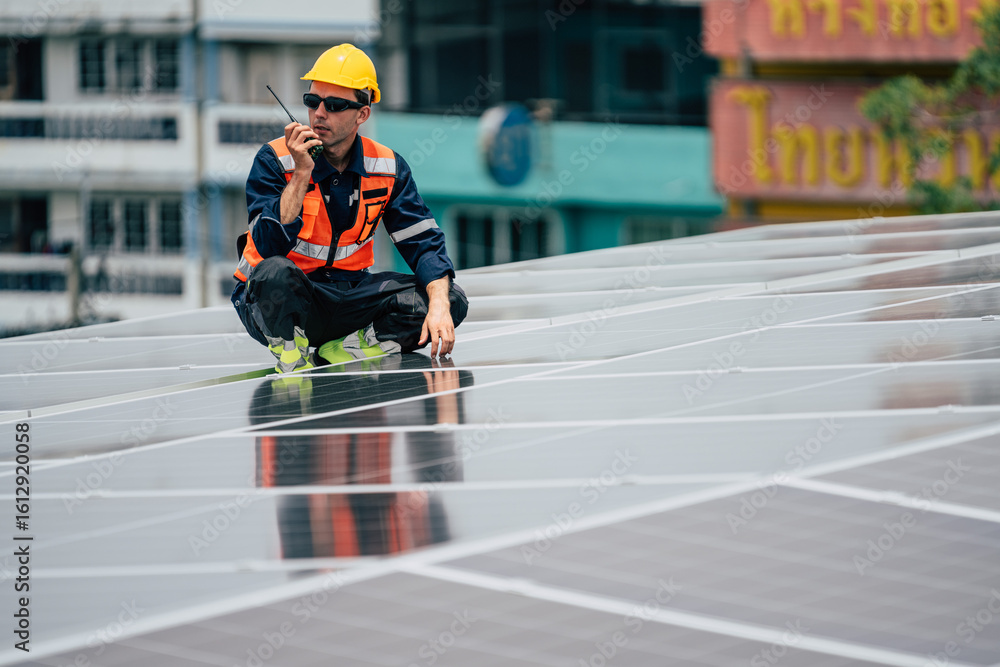 Obraz premium Worker inspects solar panels on rooftop in urban area while communicating via walkie-talkie during daylight hours