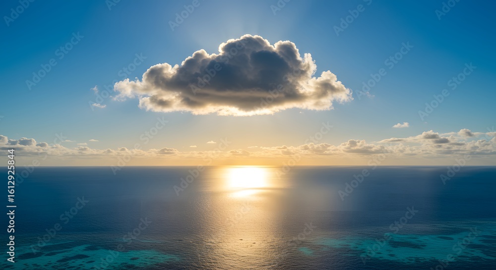 Fototapeta premium A breathtaking view of the vast ocean under a blue sky with a single cloud illuminated by the golden hour sun