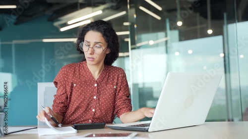 Disappointed young female employee having difficulty with task on computer while sitting at workplace in business office. Puzzled confused businesswoman cannot solve problems while working on project