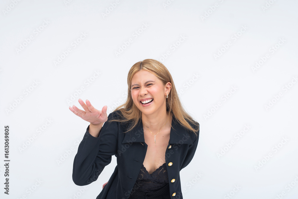 A playful young Asian woman laughing out loud with one hand raised in a friendly wave toward someone. Isolated on a white background. A playful young Asian woman laughing out loud with one hand raised in a friendly wave toward someone. Isolated on a white background.