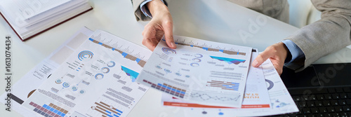 Businesswoman analyzing reports and charts at office desk