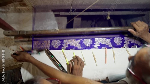 Close-up of artisan weaving Banarasi saree with gold thread work on handloom in Varanasi, India. Detailed view of hands and silk fabric in traditional textile process.
