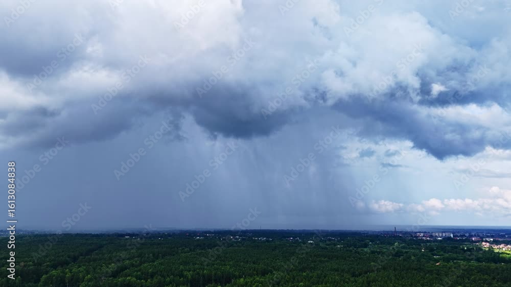 Heavy rain pours from dark dramatic clouds over a lush green forest landscape near Jelgava, Latvia, capturing the power and beauty of summer storms. Heavy rain pours from dark dramatic clouds over a lush green forest landscape near Jelgava, Latvia, capturing the power and beauty of summer storms.