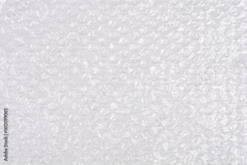 A high-angle, full-frame shot captures the textured surface of clear bubble wrap, showcasing its protective, translucent qualities as a packaging material