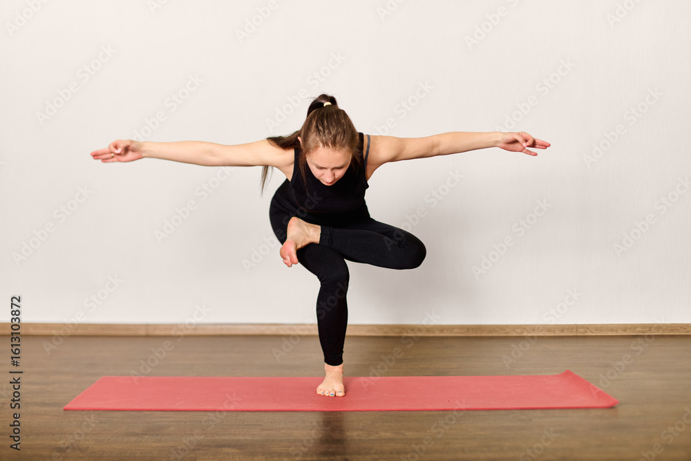 Fototapeta premium Yoga balance pose on red mat in minimalist room