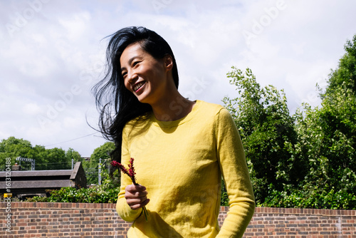 Happy person in yellow shirt smiling outdoors in London garden