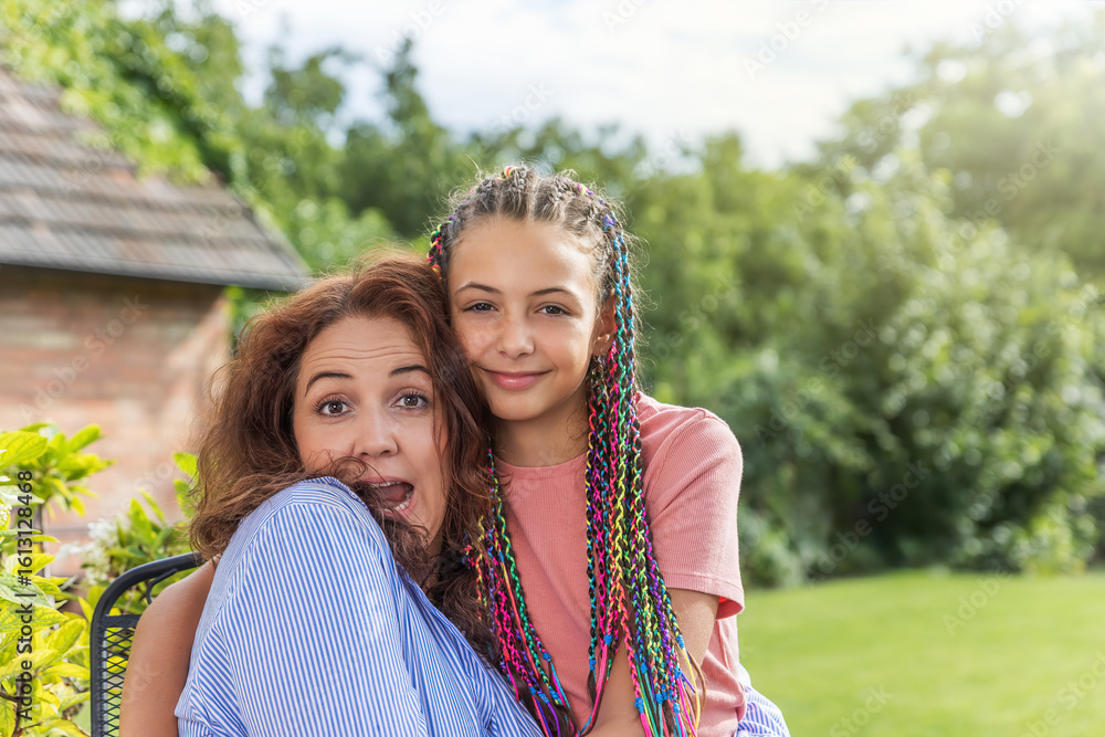 Fototapeta premium Surprised mother is sitting with her daughter in the garden. Horizontally. 
