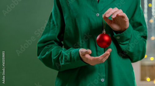Hand holding a red Christmas bauble at home for the holiday season