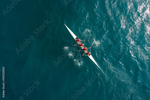 A team of four rowers rowing a racing shell in synchronization on open water.