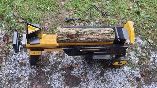 Obraz na plátně Log splitter machine splitting wood logs on snowy ground