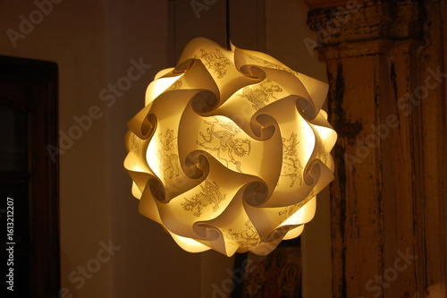 A weathered old wooden church door with a black lamp on the wall, and a red rose flower artfully placed on the handle