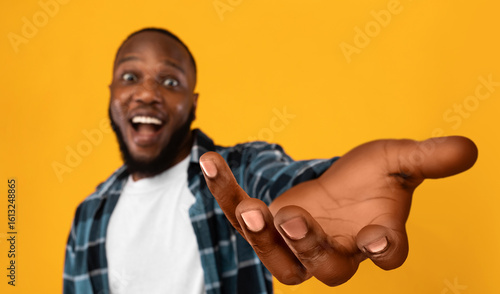 Bild auf Leinwand Happy african american guy outstretching hand, holding something invisible on hi
