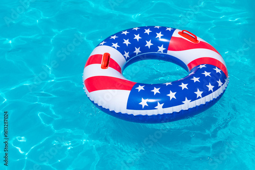 American Flag pool float. Top view of ring circle on blue water background. Summer vacation concept. Vacation in USA concept. 4th of July pool party. High quality photo