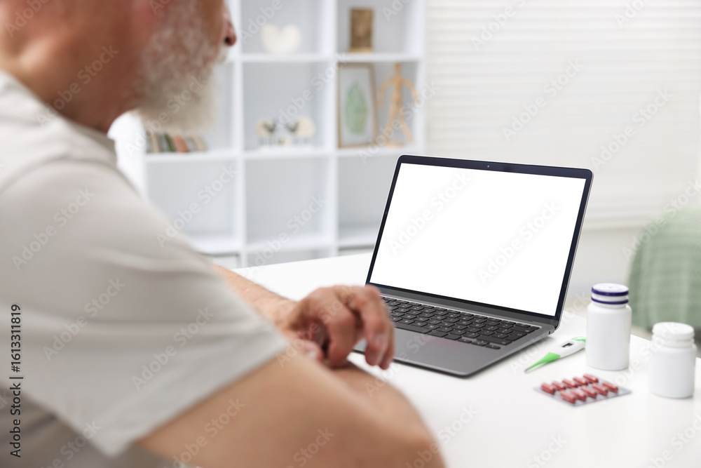 Senior man having online consultation with doctor via laptop at table indoors, closeup Senior man having online consultation with doctor via laptop at table indoors, closeup