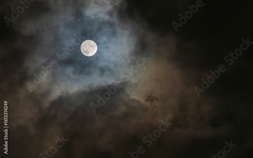 a full moon that appears through a small gap in the clouds on a cloudy night