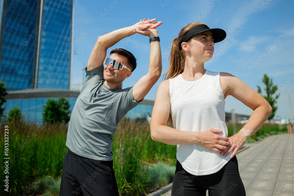 Obraz premium Fitness enthusiasts stretching in an urban park during a sunny day