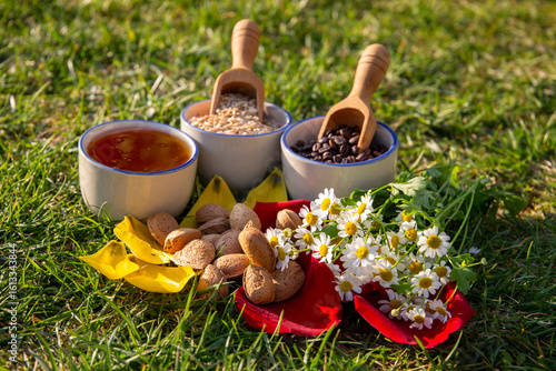 Natural Ingredients Arranged Outdoors on Grass with Honey, Grains, and Flowers