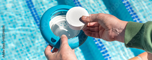 Photography Hand placing chlorine tablet in floating pool dispenser