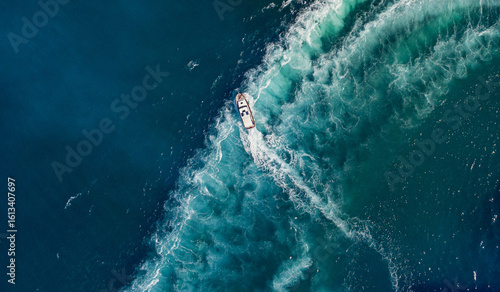 Aerial view of a boat cutting through the deep blue sea, leaving a frothy trail of white and turquoise wake behind, Split, Split-Dalmatia County, Croatia.