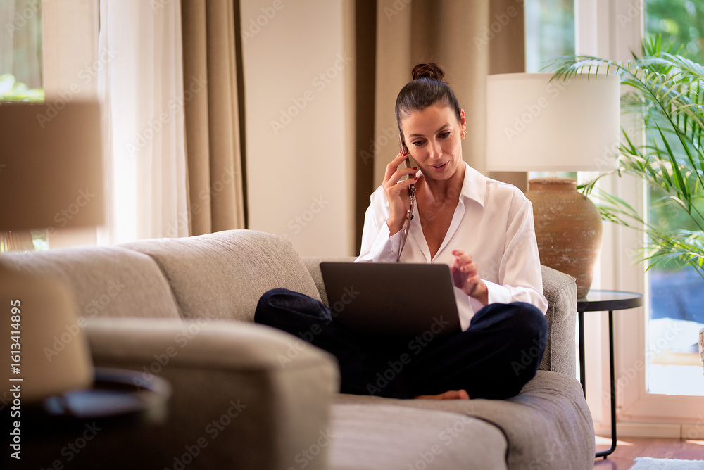 Smiling mature woman working from home, using laptop and smartphone Smiling mature woman working from home, using laptop and smartphone